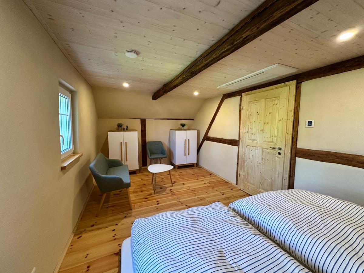 Schlafzimmer unter der Dachschräge mit Doppelbett, Sessel und Beistelltisch