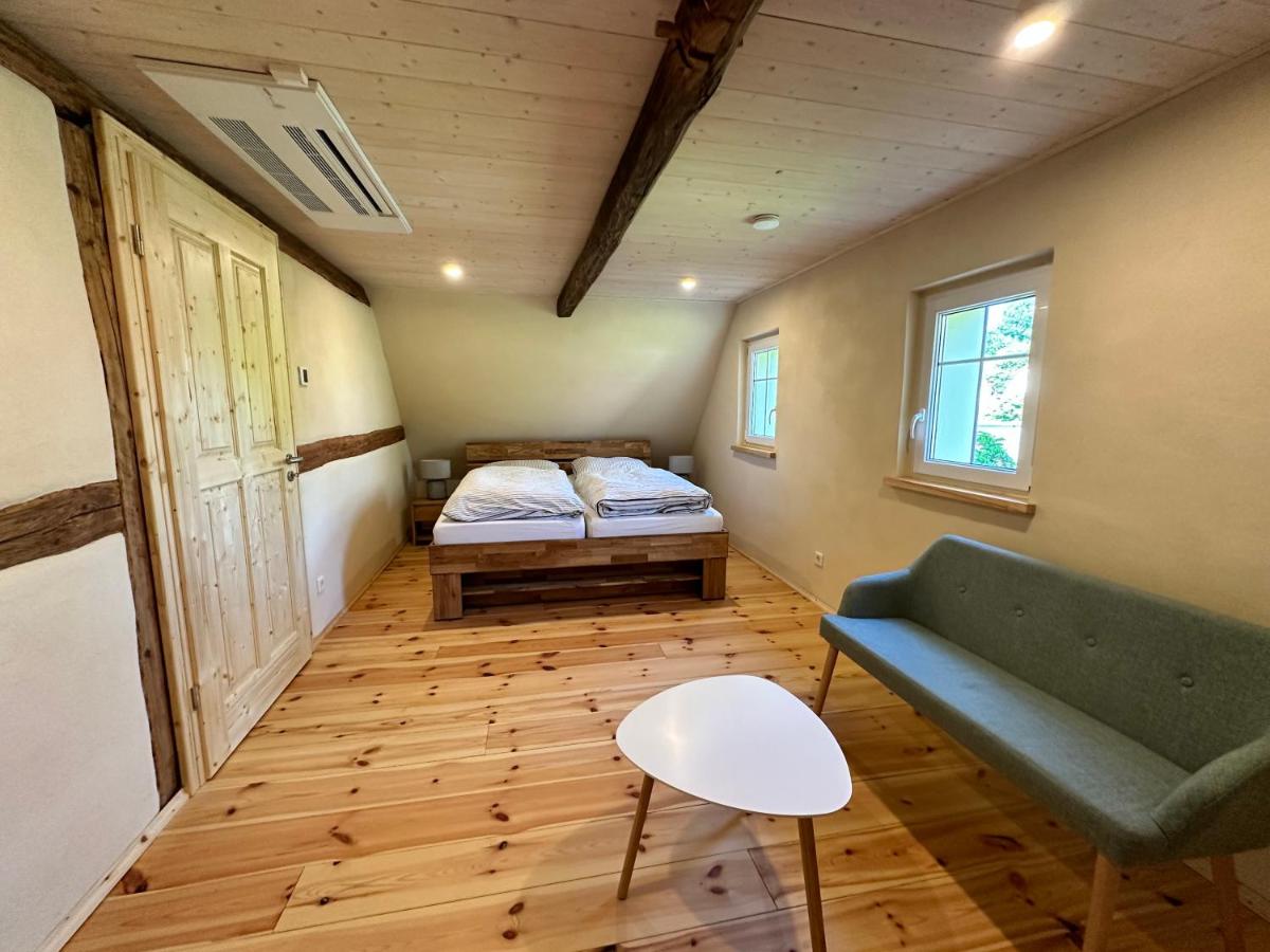 Dasselbe Schlafzimmer von der anderen Seite: Doppelbett, grünes Sofa und runder Couchtisch